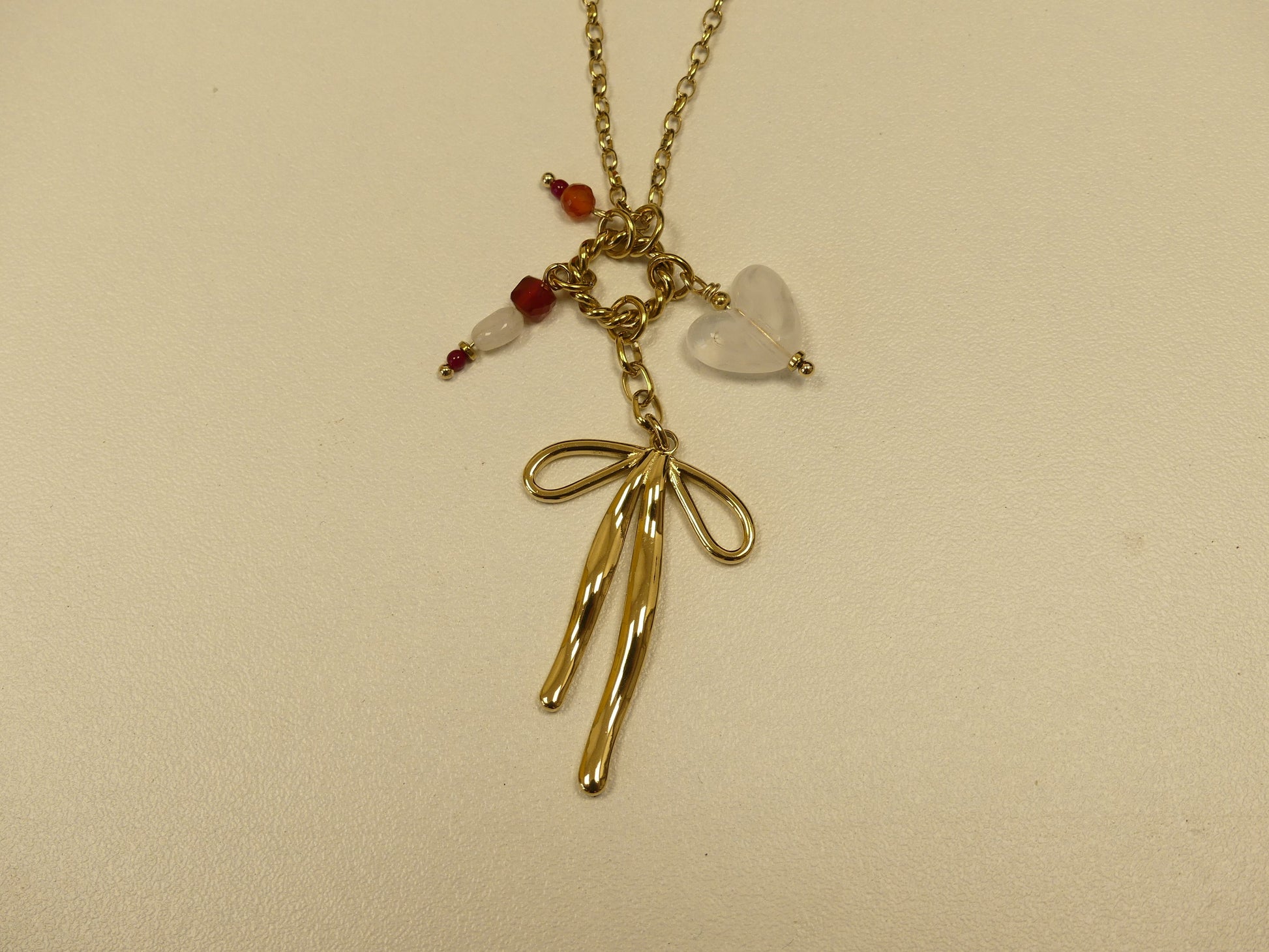 collier composé d'un anneau torsadé, noeud papillon, coeur et pierres naturelles