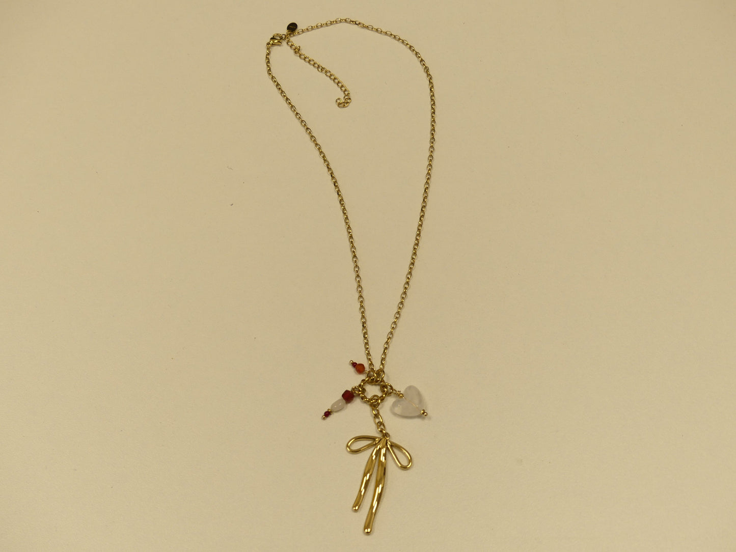 collier composé d'un anneau torsadé, noeud papillon, coeur et pierres naturelles