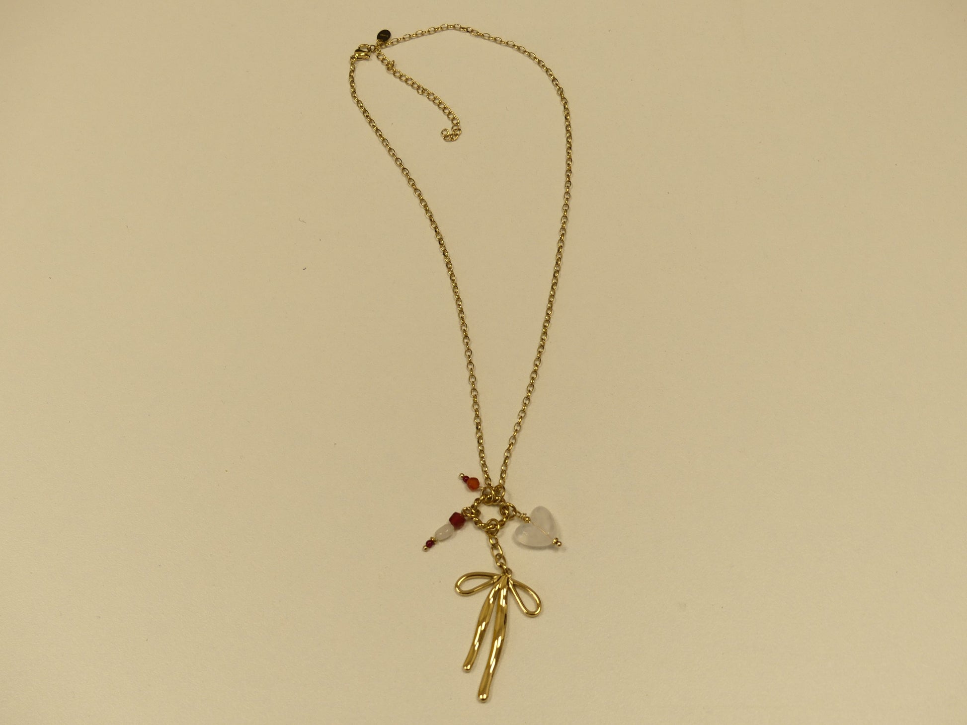 collier composé d'un anneau torsadé, noeud papillon, coeur et pierres naturelles